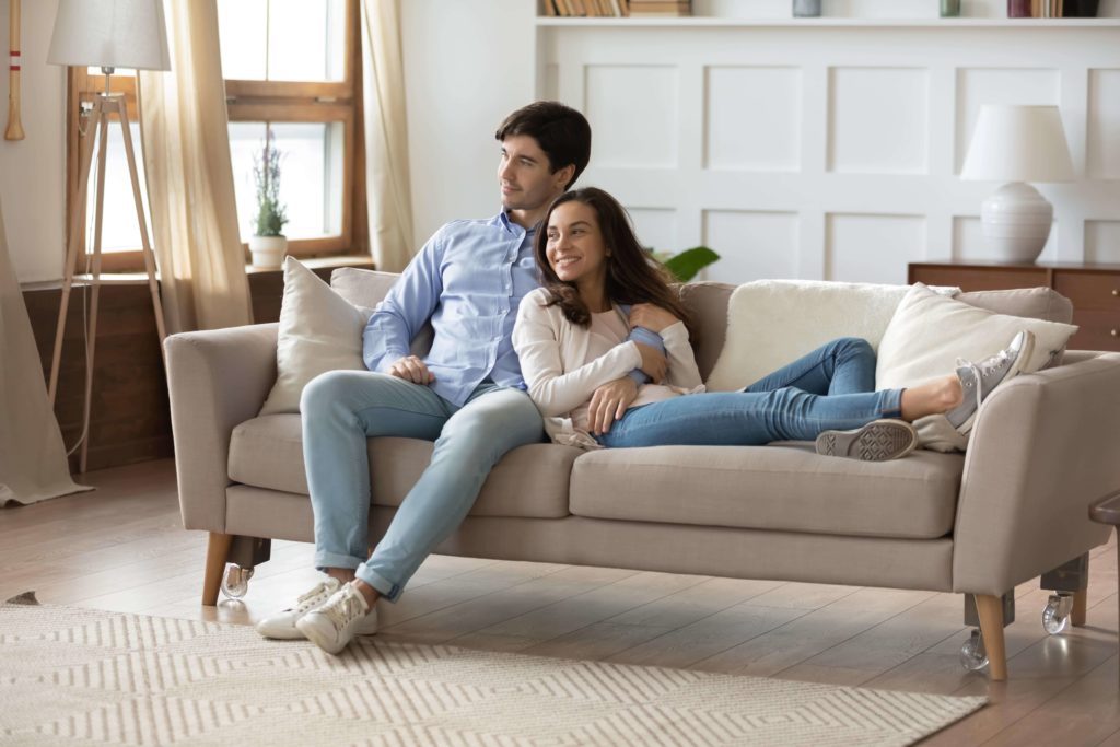 Junges Pärchen sitz innig auf dem Sofa ihre Wohnzimmers